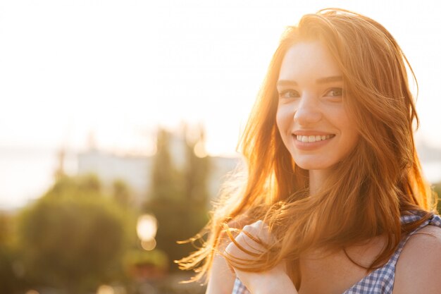 Mujer pelirroja joven sonriente con el pelo largo