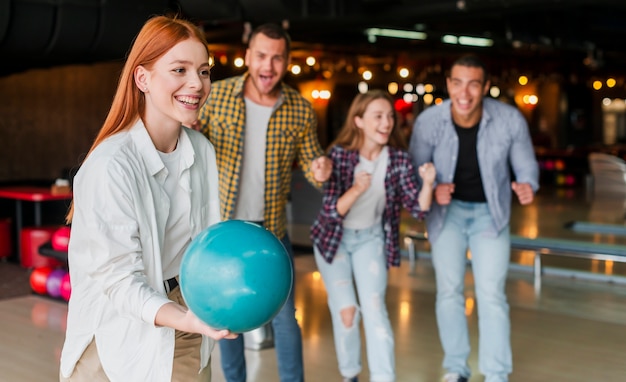 Mujer pelirroja lanzando una bola de bolos turquesa