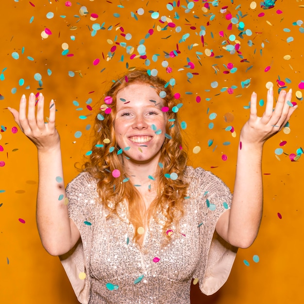 Mujer pelirroja lanzando confeti de colores