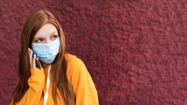 Mujer pelirroja con una mascarilla con espacio de copia