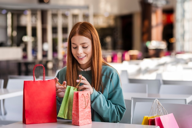 Mujer pelirroja mirando en bolsas de compras
