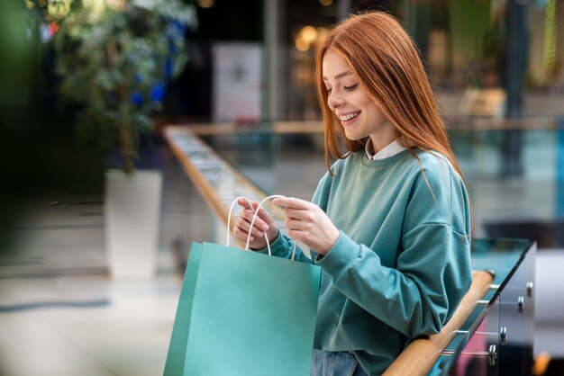 Mujer pelirroja mirando dentro de la bolsa de compras