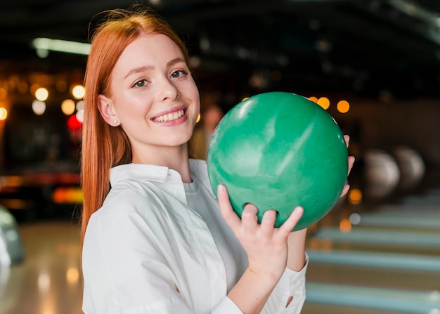 Mujer pelirroja que sostiene la bola de boliche