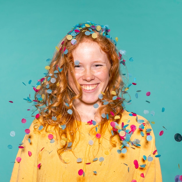 Mujer pelirroja sonriente de fiesta con confeti en el pelo