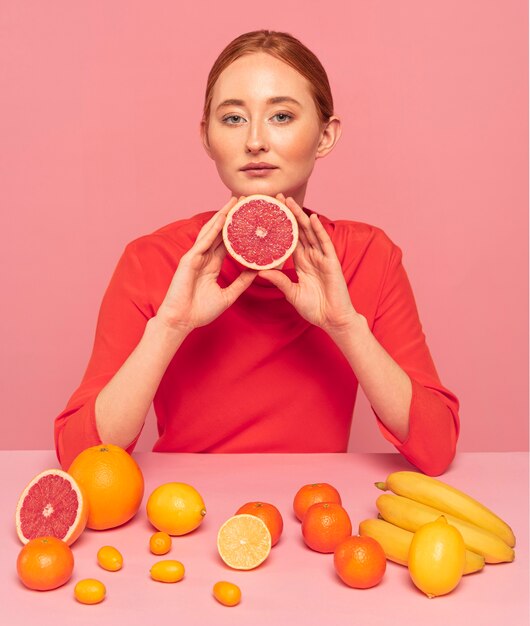 Mujer pelirroja sosteniendo un pomelo