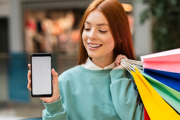 Foto gratuita mujer pelirroja sosteniendo un teléfono simulacro