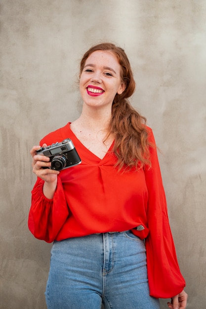 Foto gratuita mujer pelirroja de tiro medio que usa una cámara vintage