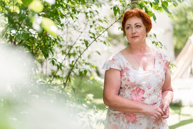 Foto gratuita mujer pelirroja en vestido floral mirando lejos