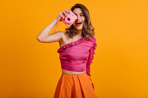 Mujer de pelo castaño rizado haciendo fotos con sonrisa