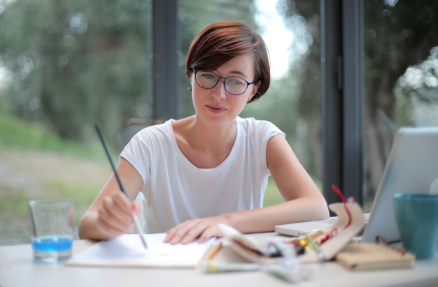 Mujer con pelo corto tratando de dibujar con un pincel en sus manos