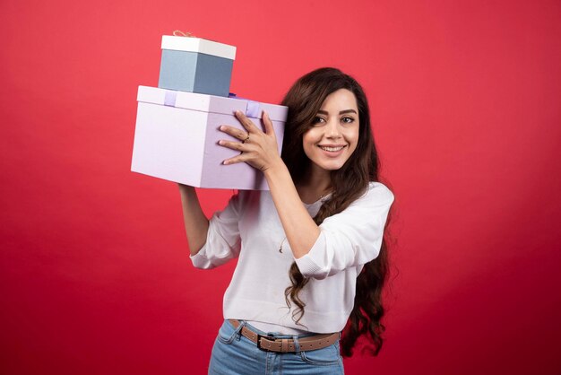 Mujer de pelo largo con cajas presentes sobre fondo rojo. Foto de alta calidad