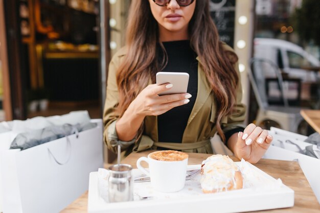 Foto gratuita mujer de pelo largo con manicura blanca tomando la fotografía de su almuerzo en la cafetería al aire libre