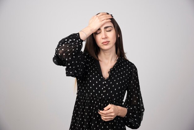 Mujer de pelo largo en vestido negro con cefalea.