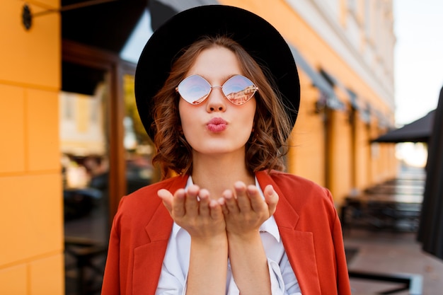 Mujer de pelo muy corto enviando beso de aire. Elegante look otoñal.