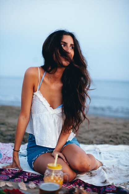 Mujer con el pelo ondulado sentada en la playa