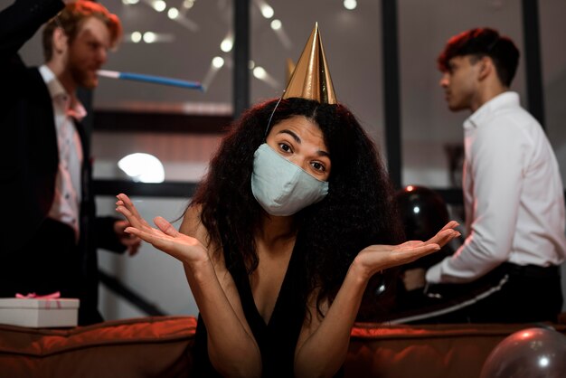 Mujer de pelo rizado con una máscara médica en la fiesta de fin de año