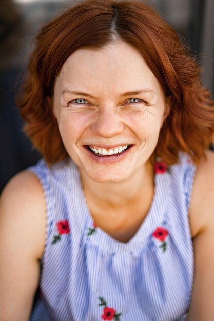 mujer con pelo rojo en un café bebe un cóctel de verano, feliz, ríe, sonríe.