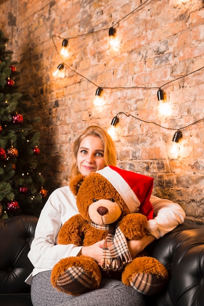 Mujer con peluche que lleva gorro de navidad