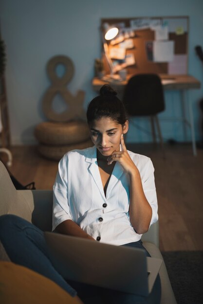 Mujer de pensamiento trabajando en la computadora portátil desde casa