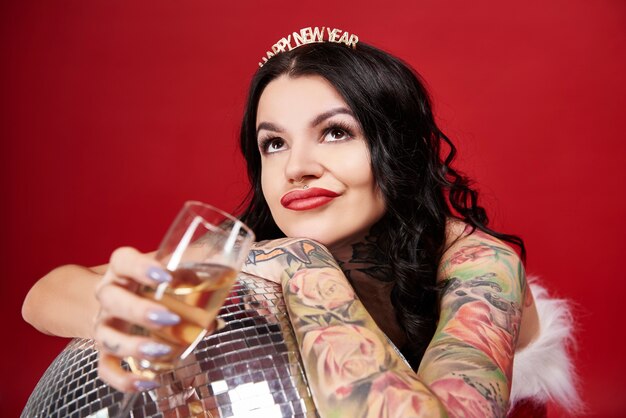 Foto gratuita mujer pensativa con bola de discoteca bebiendo champán y mirando hacia arriba