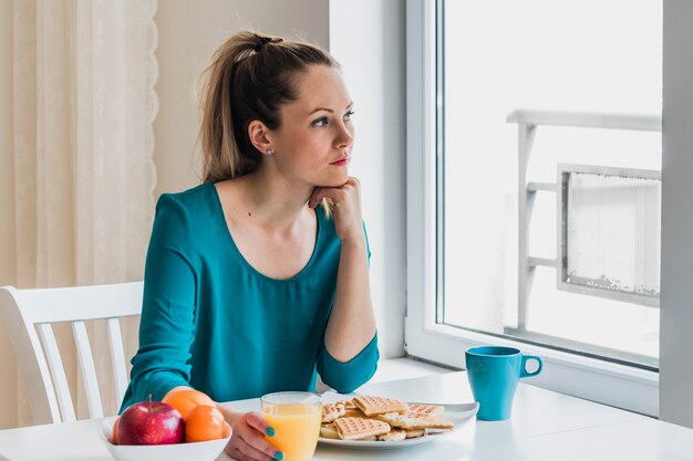 Mujer pensativa desayunando