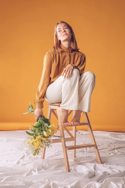 Foto gratuita mujer pensativa en escalera con ramo de flores