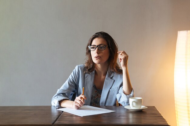 Mujer pensativa escribiendo notas.