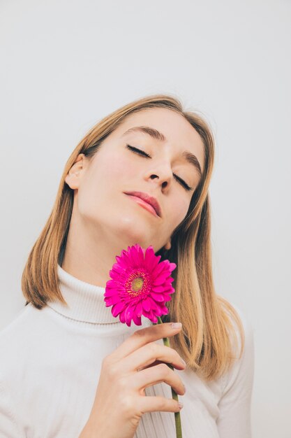 Mujer pensativa con flor de gerbera