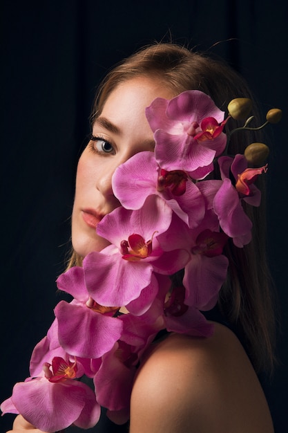 Foto gratuita mujer pensativa con flor rosa brillante