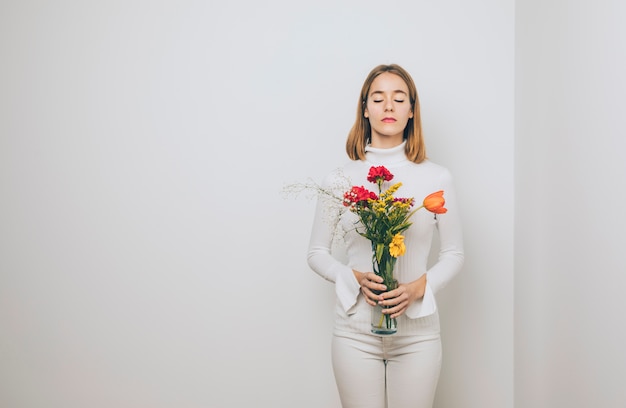Foto gratuita mujer pensativa con flores brillantes en florero