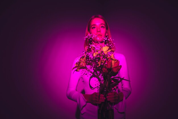 Mujer pensativa con flores brillantes en florero