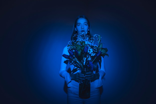 Mujer pensativa con flores en florero de vidrio