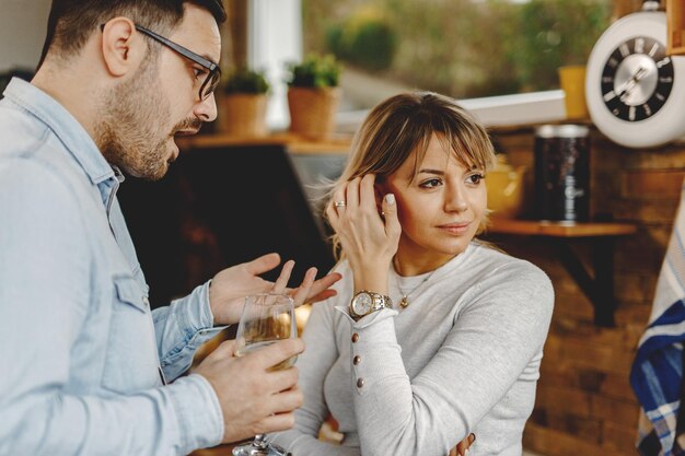 Mujer pensativa mirando hacia otro lado mientras su novio intenta hablar con ella en la cocina