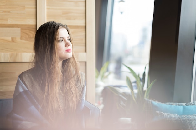 Mujer pensativa mirando a través de la ventana