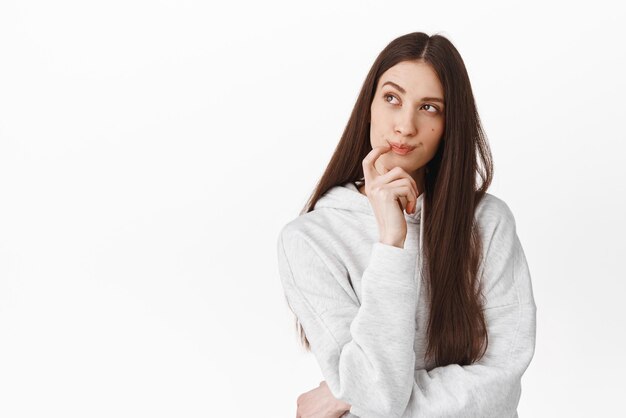 Mujer pensativa pensando qué orden de comida buscando pensativa haciendo una elección o imaginando algo reflexionando de pie sobre fondo blanco Copiar espacio