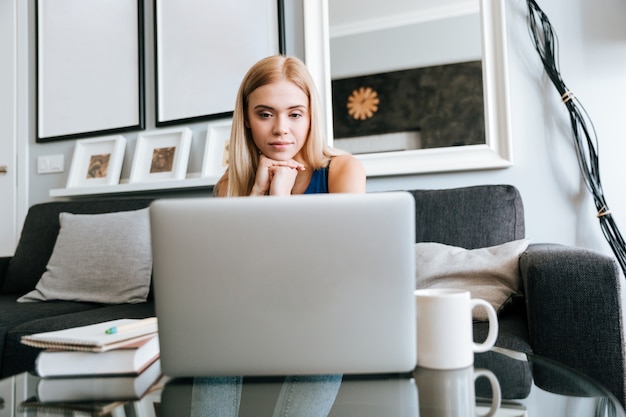 Mujer pensativa pensando y usando la computadora portátil en casa