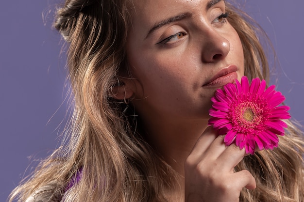 Mujer pensativa posando mientras sostiene un crisantemo