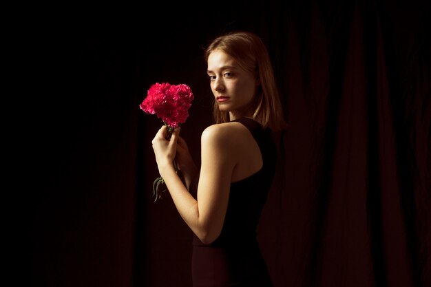 Mujer pensativa que se coloca con las flores rosadas