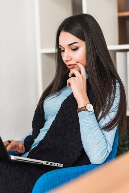 Mujer pensativa que usa la computadora portátil