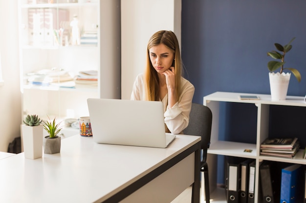 Mujer pensativa que usa la computadora portátil