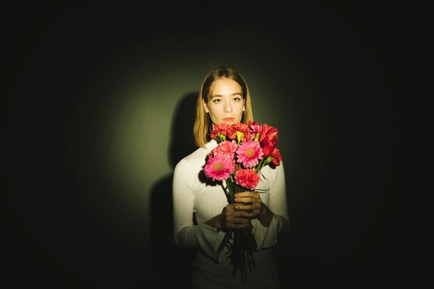 Mujer pensativa con ramo de flores.