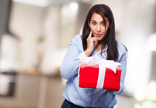 Mujer pensativa con un regalo rojo