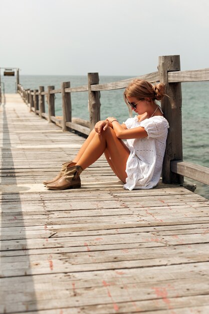 Mujer pensativa sentado en un muelle