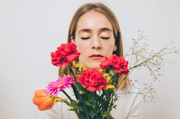 Foto gratuita mujer pensativa sosteniendo flores brillantes