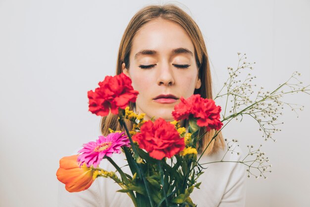 Mujer pensativa sosteniendo flores brillantes