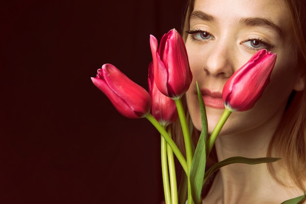 Mujer pensativa con tulipanes rojos