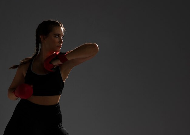 Mujer perforando con guantes de box y espacio de copia