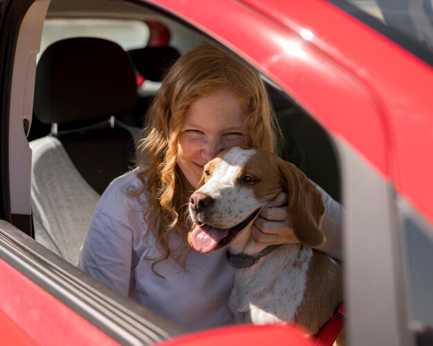 Mujer y perro feliz dando un paseo con el coche