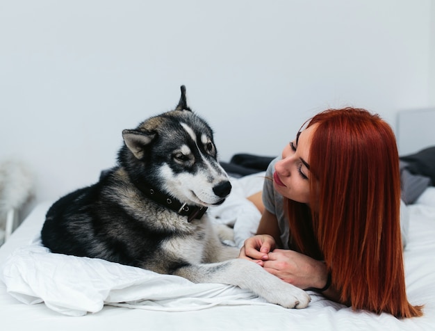 Mujer con perro grande en la cama