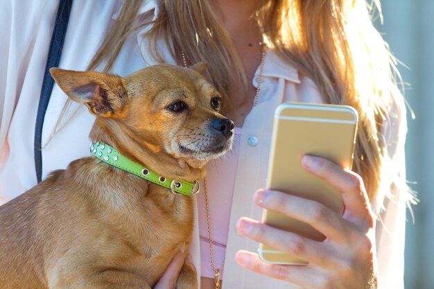 Mujer con el perro en las manos usando teléfonos inteligentes